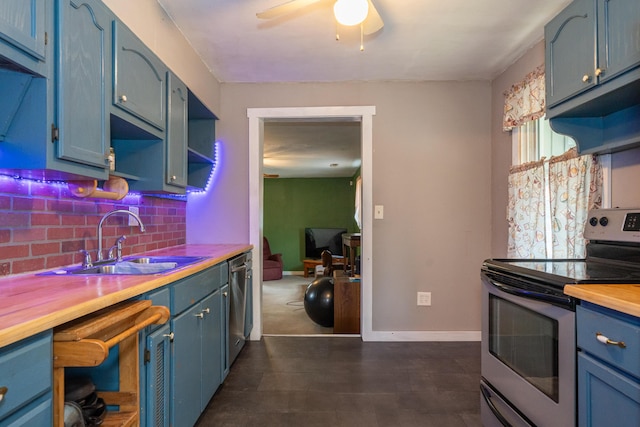 kitchen featuring blue cabinetry, butcher block countertops, sink, stainless steel appliances, and backsplash