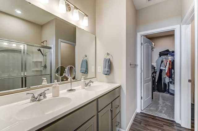 bathroom with hardwood / wood-style flooring, vanity, and a shower with door