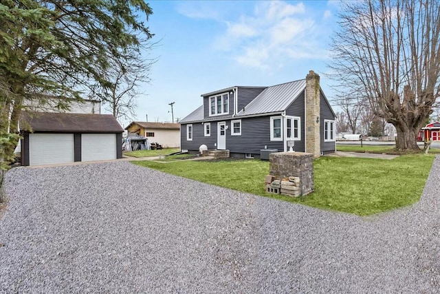 view of front of home with a front yard, a chimney, an outbuilding, metal roof, and entry steps