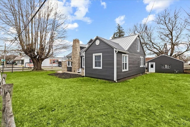 view of home's exterior with a chimney, fence, a yard, and metal roof