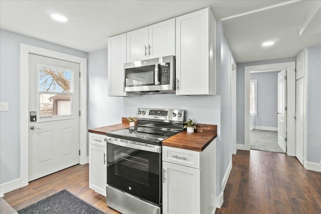 kitchen with white cabinets, butcher block countertops, dark wood-style flooring, and appliances with stainless steel finishes