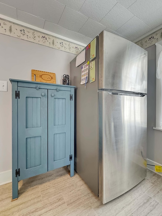 interior space featuring blue cabinets, baseboards, and freestanding refrigerator