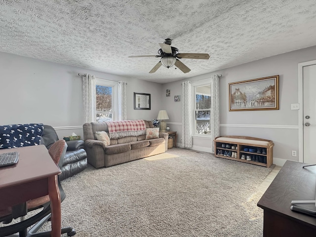 living area featuring carpet floors, ceiling fan, and a textured ceiling