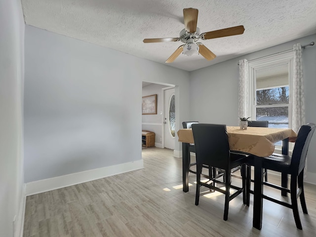 dining area with a textured ceiling, ceiling fan, wood finished floors, and baseboards