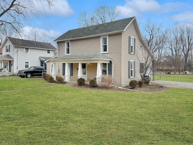 view of front facade with covered porch, fence, and a front lawn