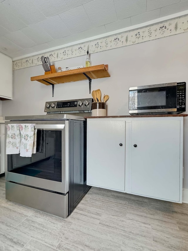 kitchen with open shelves, white cabinetry, and stainless steel appliances