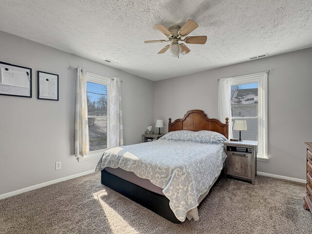 carpeted bedroom featuring a textured ceiling, ceiling fan, visible vents, and baseboards