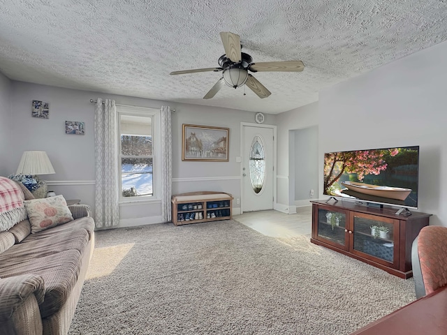 living room featuring carpet floors, ceiling fan, a textured ceiling, and baseboards