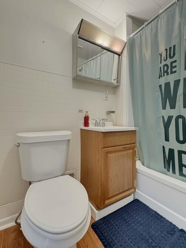 bathroom with tile walls, toilet, shower / bath combo with shower curtain, vanity, and wood finished floors