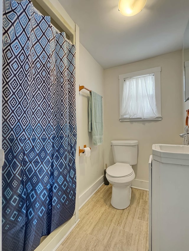 bathroom featuring a shower with curtain, baseboards, vanity, and toilet