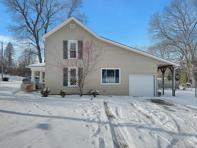 view of snow covered exterior featuring a garage and fence