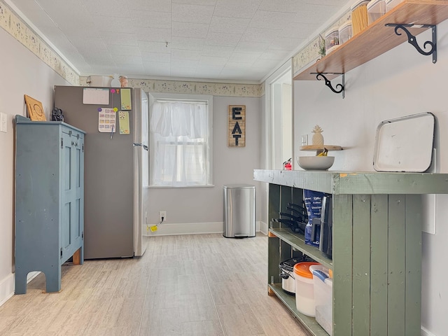 kitchen with freestanding refrigerator, open shelves, baseboards, and wood finished floors