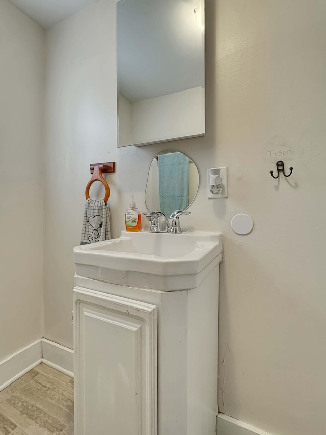 bathroom with wood finished floors, vanity, and baseboards