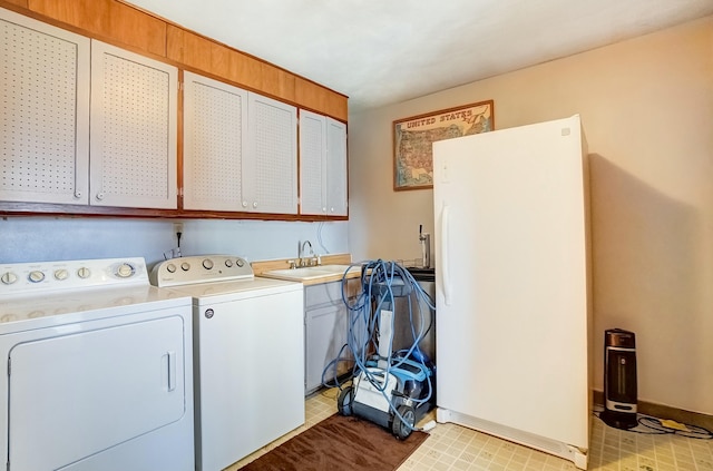 washroom featuring a sink, baseboards, cabinet space, and separate washer and dryer