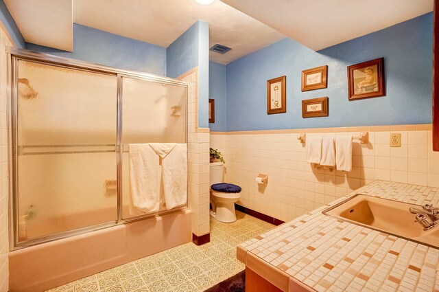 full bath featuring tile patterned flooring, visible vents, toilet, tile walls, and a sink