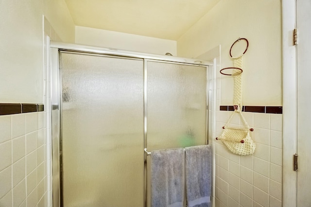 bathroom featuring a wainscoted wall, a shower stall, and tile walls