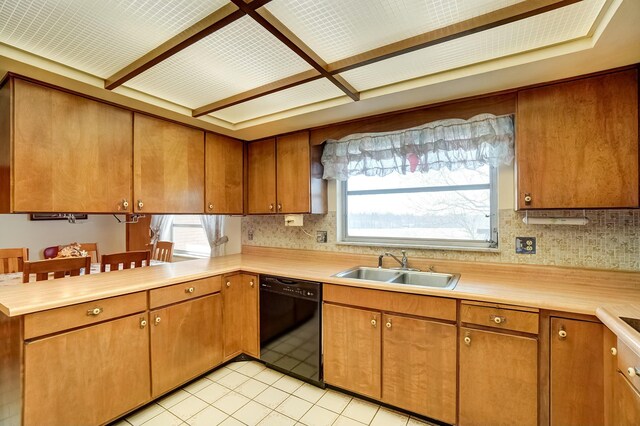 kitchen featuring backsplash, light countertops, black dishwasher, brown cabinets, and a sink