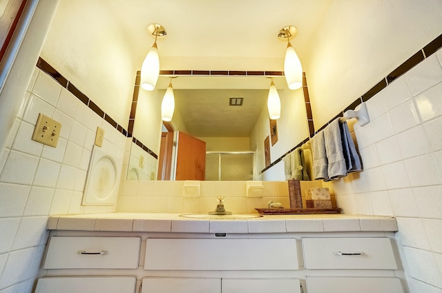 full bathroom featuring vanity, tile walls, and a shower stall