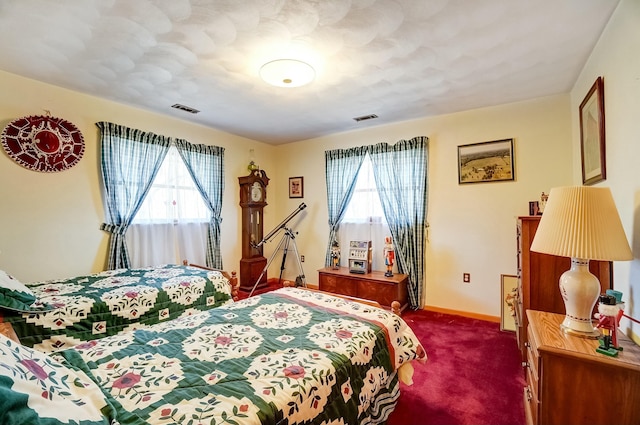 bedroom with visible vents, baseboards, and dark carpet