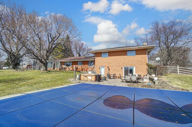 back of property featuring brick siding, fence, a chimney, a yard, and a patio