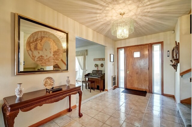 foyer entrance with a wealth of natural light, baseboards, an inviting chandelier, and light tile patterned flooring