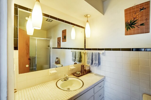 bathroom with visible vents, tile walls, a stall shower, and vanity