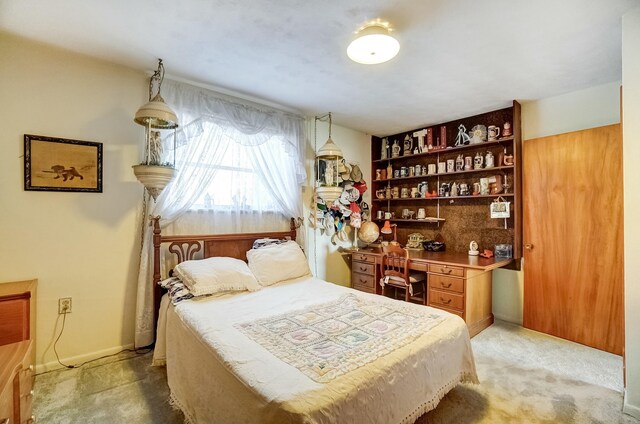 bedroom with baseboards, light carpet, and built in desk