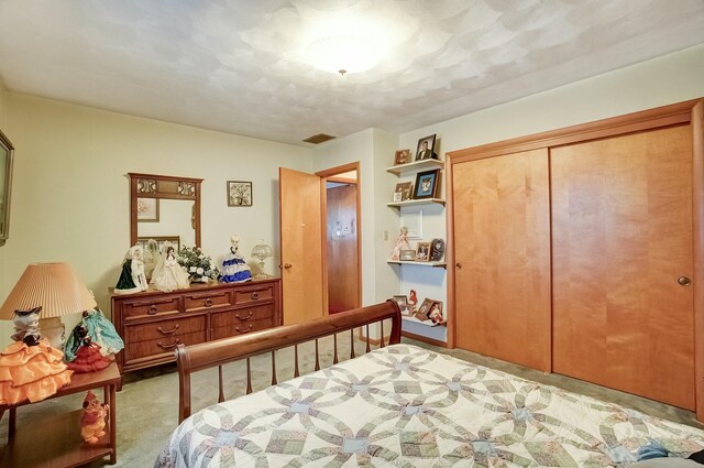 bedroom with a closet, visible vents, and light carpet