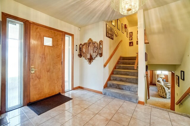 entrance foyer featuring stairs, an inviting chandelier, light tile patterned floors, and baseboards