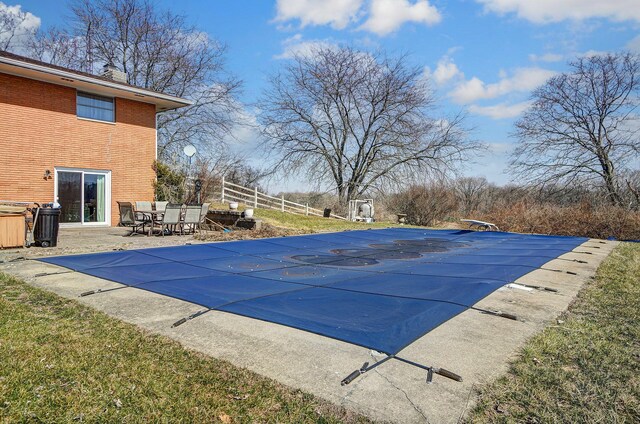 view of swimming pool featuring a covered pool, a diving board, a patio, and fence