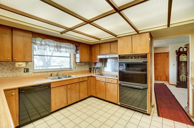 kitchen with a sink, black appliances, under cabinet range hood, and light countertops