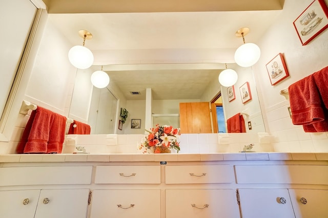 bathroom featuring an enclosed shower, backsplash, and double vanity