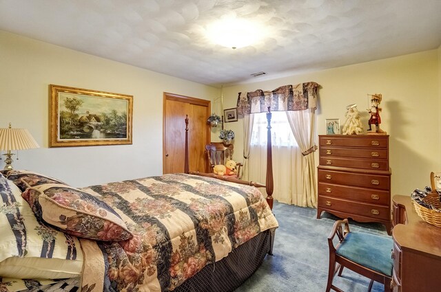 bedroom with a closet, visible vents, and dark carpet