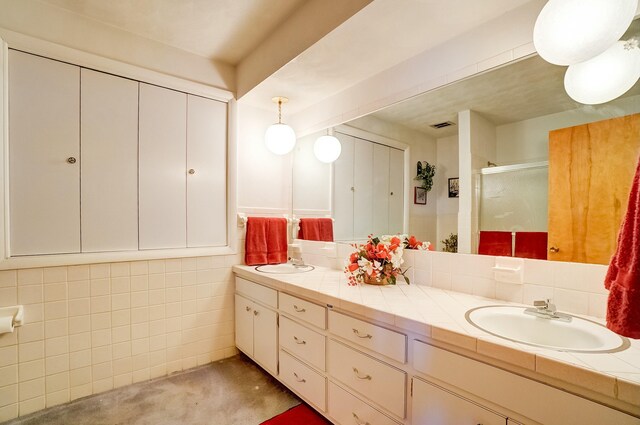 full bath with a sink, visible vents, double vanity, and a shower stall