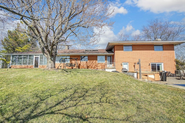 rear view of property featuring brick siding, roof mounted solar panels, a patio, and a yard