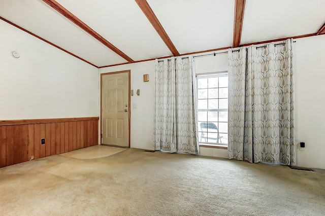 unfurnished room with visible vents, vaulted ceiling with beams, wood walls, wainscoting, and carpet flooring