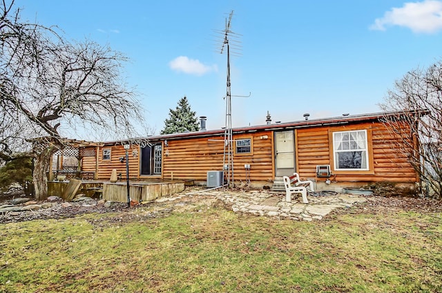 rear view of property featuring cooling unit, a wooden deck, and a yard