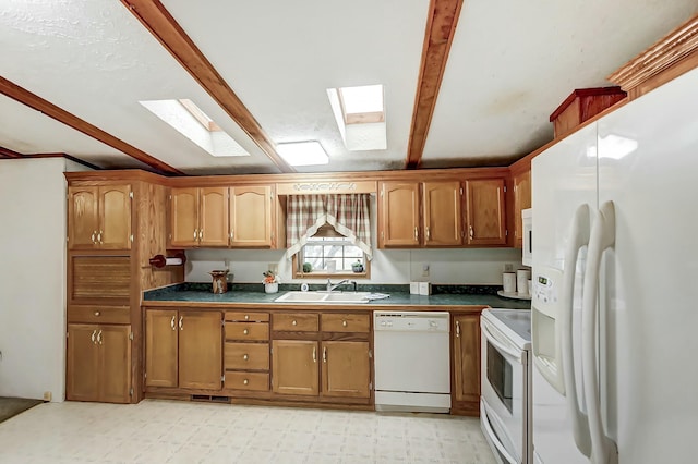 kitchen featuring dark countertops, light floors, brown cabinets, white appliances, and a sink