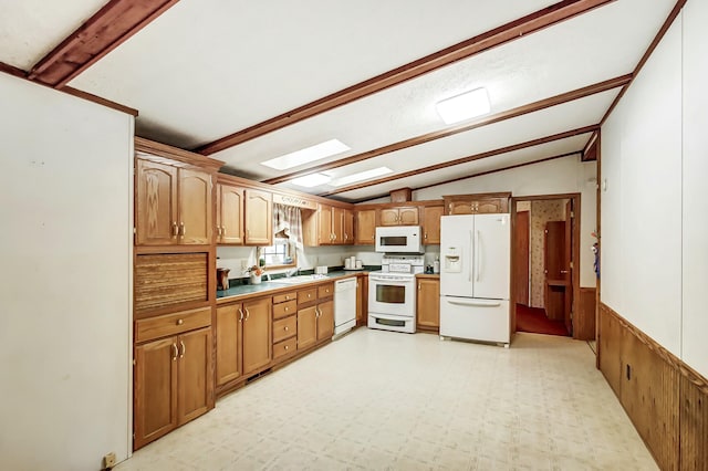 kitchen with lofted ceiling with skylight, a wainscoted wall, light floors, brown cabinetry, and white appliances