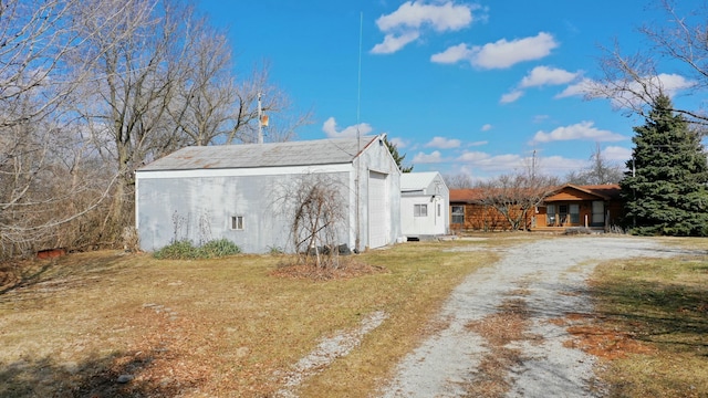 exterior space featuring an outbuilding, a garage, covered porch, and dirt driveway