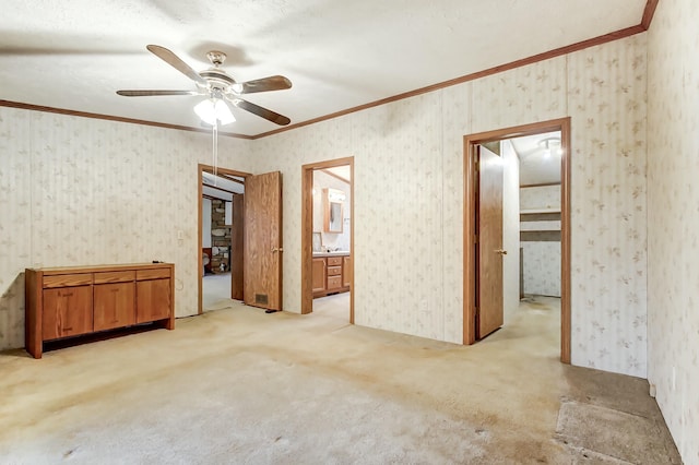 unfurnished room featuring wallpapered walls, ornamental molding, a ceiling fan, and light carpet