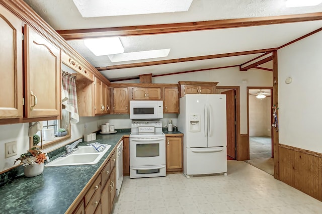 kitchen featuring a sink, white appliances, dark countertops, and vaulted ceiling with skylight