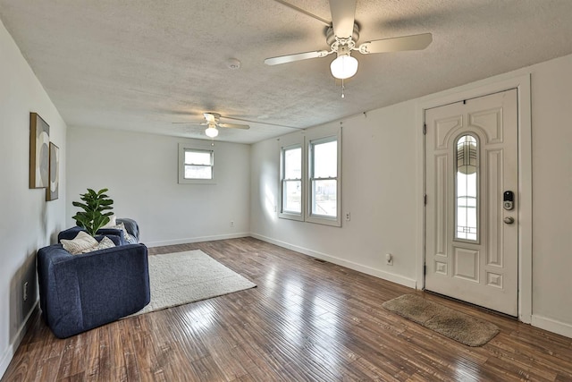 foyer with a textured ceiling, wood finished floors, visible vents, and baseboards