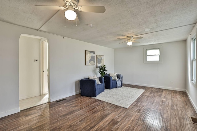 living area featuring visible vents, a textured ceiling, arched walkways, and wood finished floors