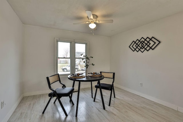 dining space featuring a ceiling fan, light wood-style flooring, and baseboards