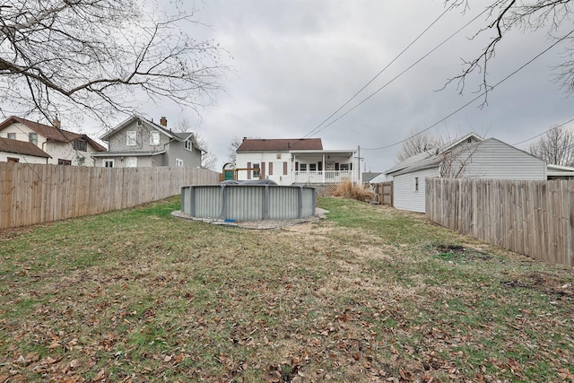 rear view of property with a yard, a fenced backyard, and a fenced in pool