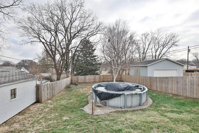 view of yard featuring a fenced in pool, a fenced backyard, and a garage