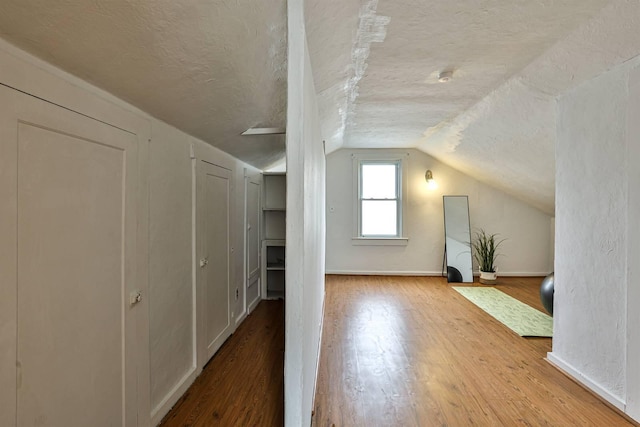 bonus room with lofted ceiling, a textured ceiling, baseboards, and wood finished floors