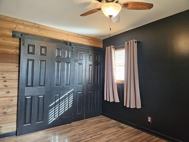 foyer featuring hardwood / wood-style flooring, ceiling fan, and wood walls