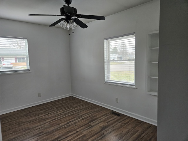 spare room with ceiling fan, a wealth of natural light, and dark hardwood / wood-style flooring